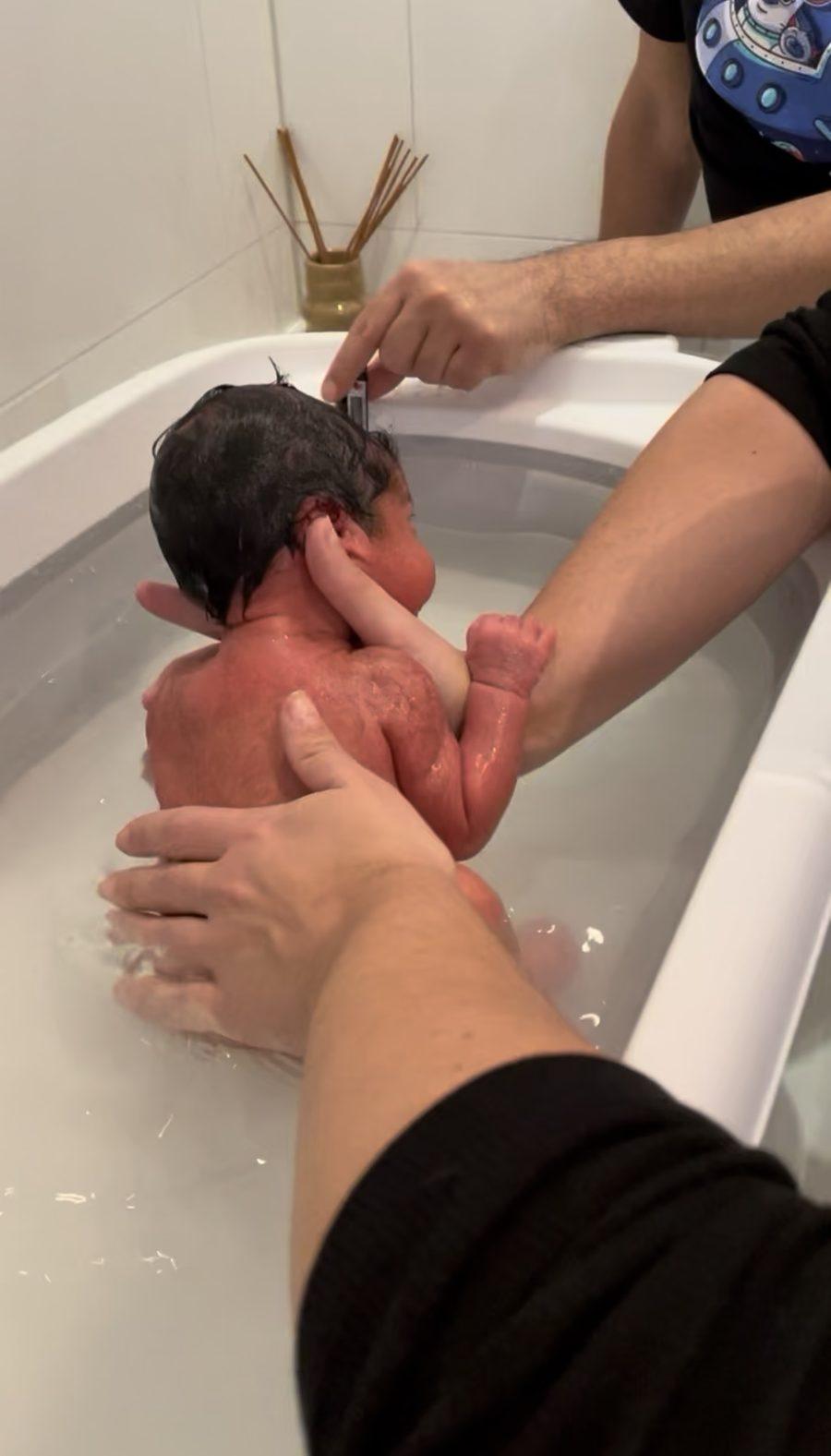 A newborn baby being gently bathed in a baby bath